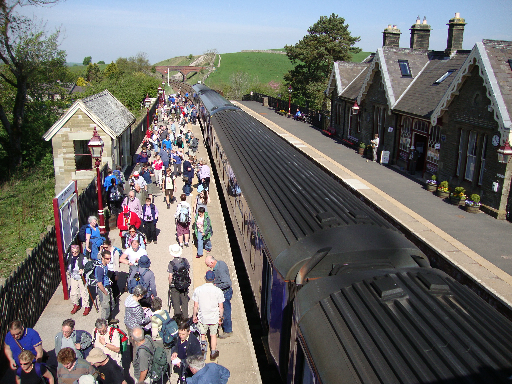 Train at a station with a crowd of people waiting to get on board. Taste your way by train this summer.